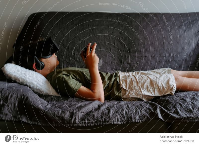 Little boy in VR headset relaxing on couch at home child sofa vr goggles gamepad play device entertain digital innovation gadget modern little casual experience