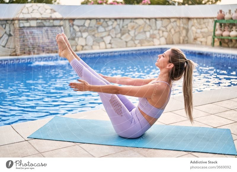 Woman in Boat pose on yoga mat boat pose practice woman balance active wear poolside summer flexible concentrate female wellness body asana courtyard relax