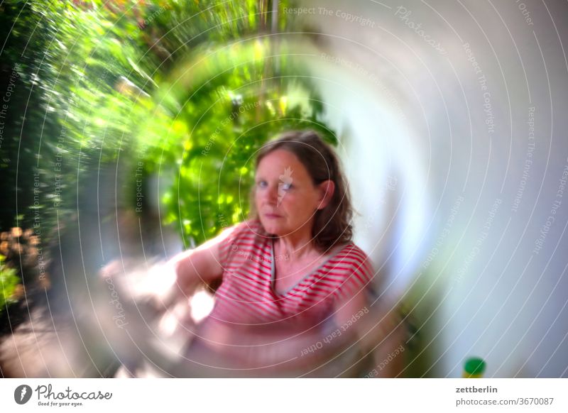 Woman, viewed through a glass portrait Sit Garden holidays Relaxation allotment holiday weekend local recreation Weekend Looking eye contact blurred Glass Lens