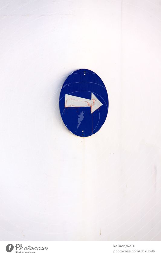 Round blue sign with white arrow on a white wall Arrow Blue White Wall (building) Right Direction off One-way street Greece Southern Europe Portrait format