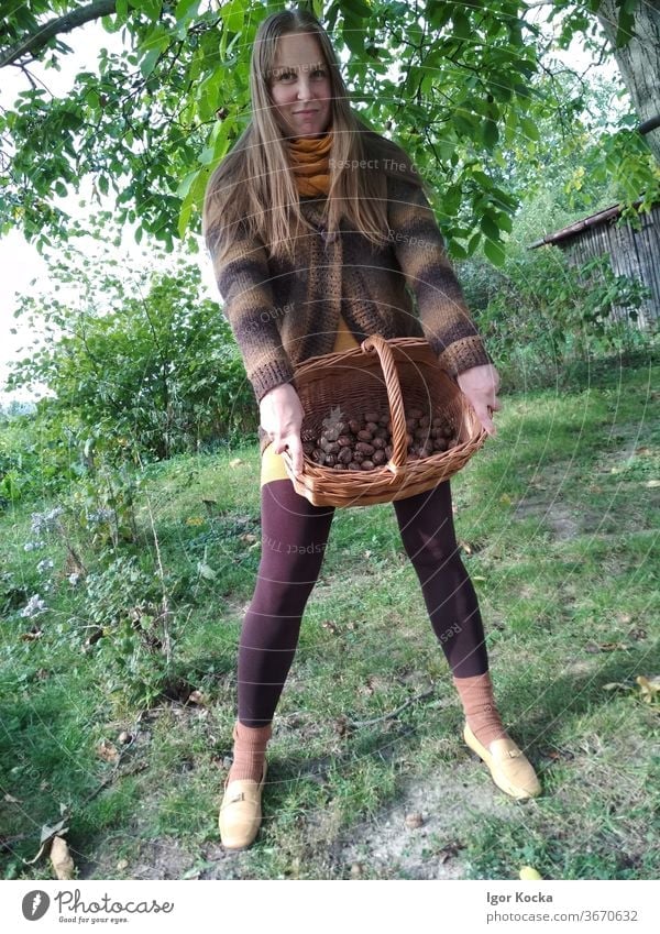 Portrait of beautiful woman holding basket with wallnuts Woman female Basket standing portrait happy smiling cheerful lifestyle Brown warm clothes casual
