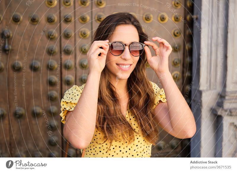 Charming woman smiling in city trendy style ancient fashion sunglasses gate ornament smile female street urban young positive happy cloth metal door historic