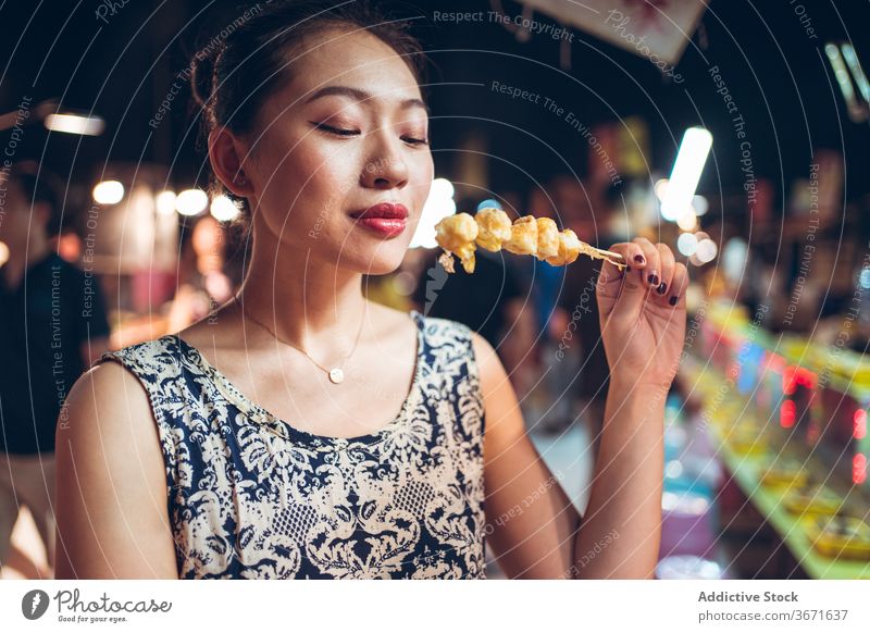 Happy woman with fried quail eggs on street street food eat delicious zhubei night market female taiwan asian ethnic stick tradition tasty nutrition asian food