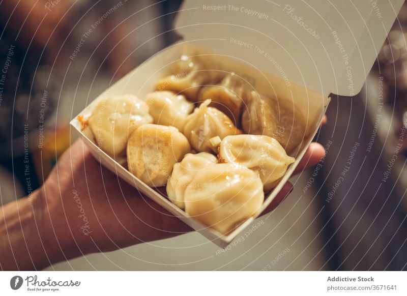 Crop person with fried dumplings in paper container street food market tasty zhubei taiwan yummy city meal evening cuisine retail gourmet customer buyer sell