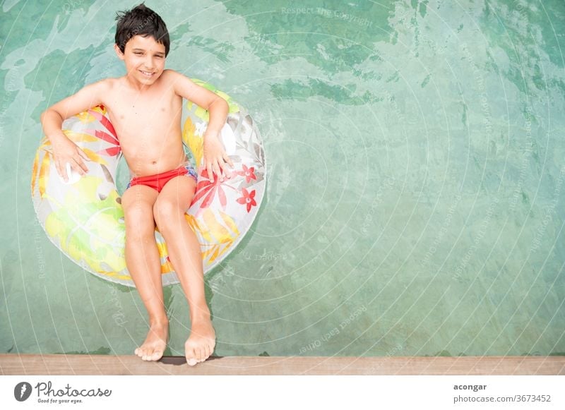 Boy floating on an inflatable circle in the pool. Child blue boy carefree caucasian childhood comfortable cool cute enjoyment float tube flower fun happiness