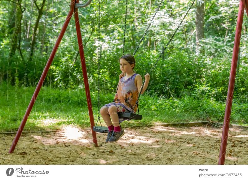 Little girl on a swing in the forest Child Playing Joy Summer Movement Playground Toddler feet motor function Schoolyard Meadow Play instinct Infancy Gymnastics