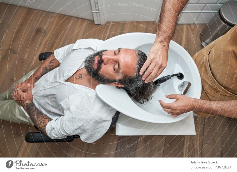 Barber washing hair of male client in salon men barber head sink customer barbershop workplace hairdresser haircut hairstylist service beard care professional