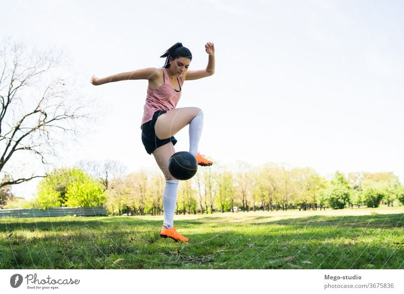 Young female soccer player practicing on field. young woman football focused exercising athleticism trick summer sports activity recreational players