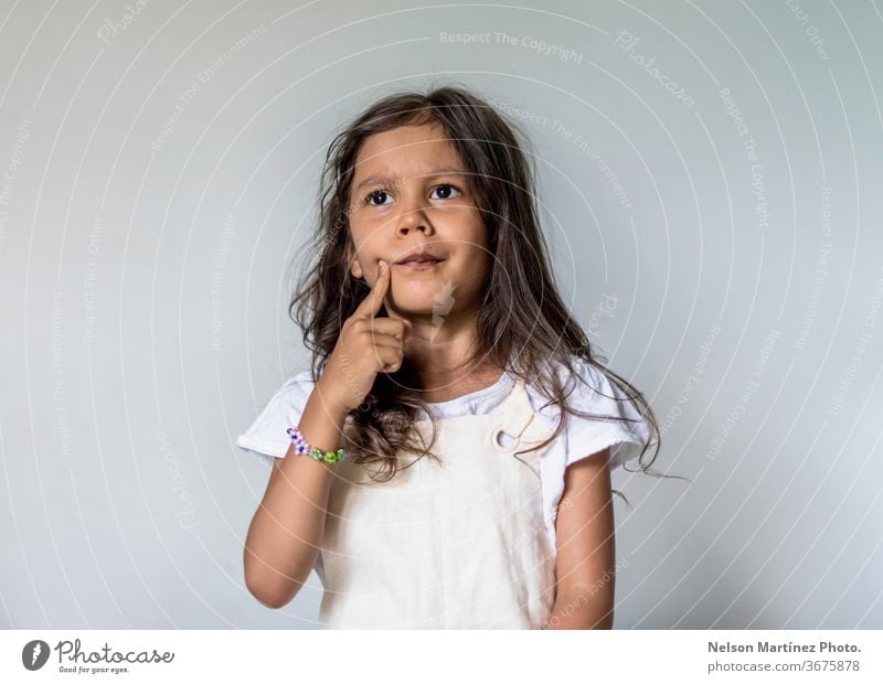 Thoughtful little girl in her bedroom. She is thinking and confused. learning school concentration idea pondering study hispanic misunderstanding Education