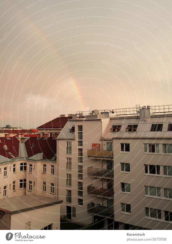A rainbow stretches over the city Rainbow Nature Natural phenomenon Weather sunshine Sky Clouds colors Town houses apartment buildings roofs Architecture