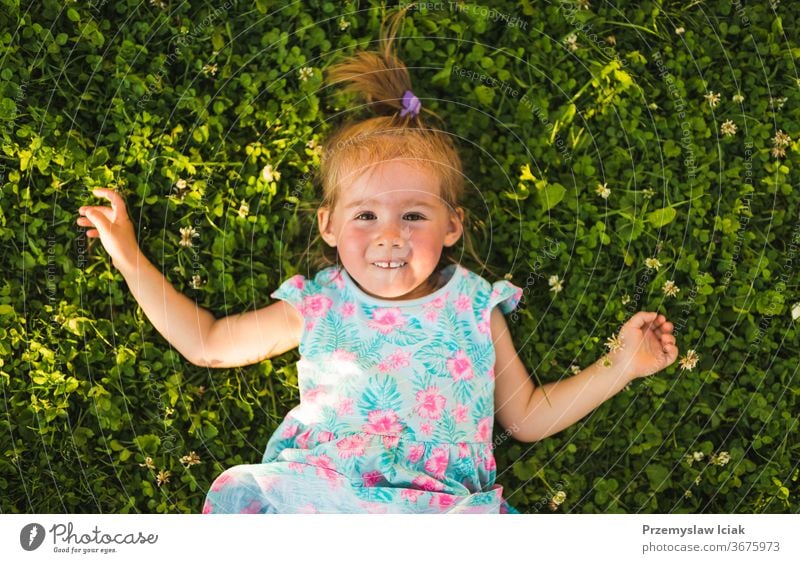 Beautiful baby girl lying on grass laughing and looking up. childhood 2-3 happines adorable cute nature laughing fun emotions smile above shoot sunset summer
