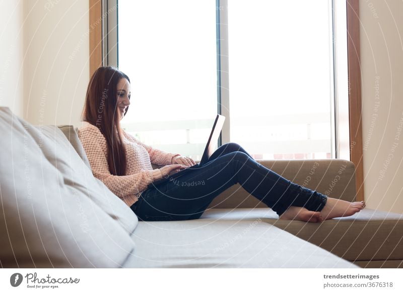 Woman on couch with laptop woman home sofa young using happy technology room sitting beautiful digital casual female indoors person modern internet pretty