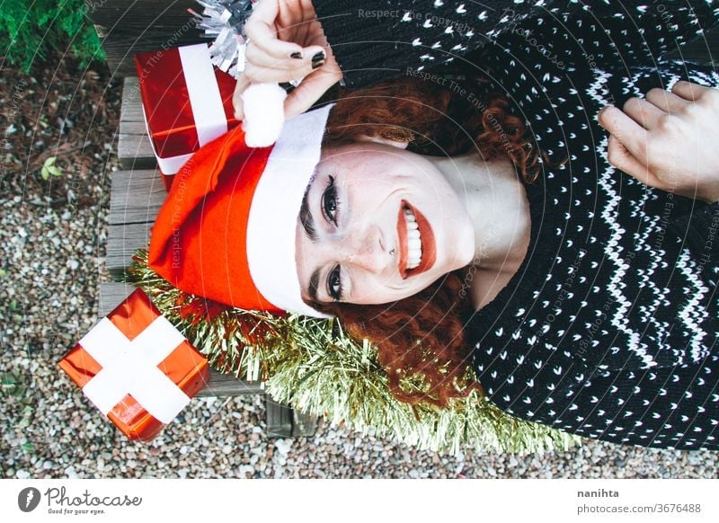 Young redhead woman lying down in a bench wearing  a christmas outfit holidays gift people real pretty young youth happy happiness merry christmas decor
