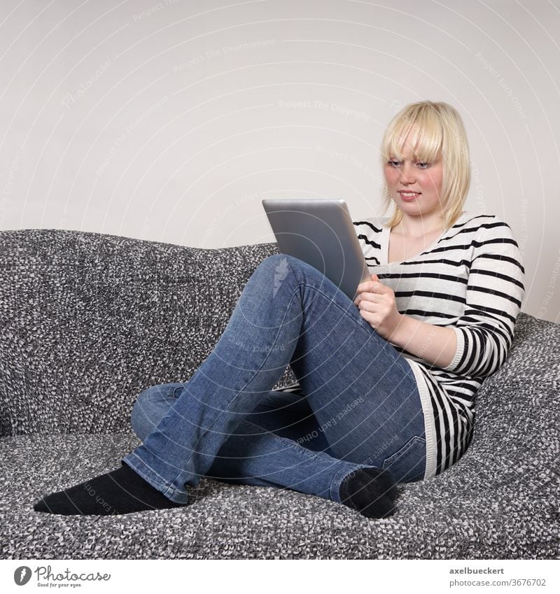 young woman using tablet pc computer girl entertainment e-learning sofa couch student smiling home living room lifestyle holding sitting relaxing reading