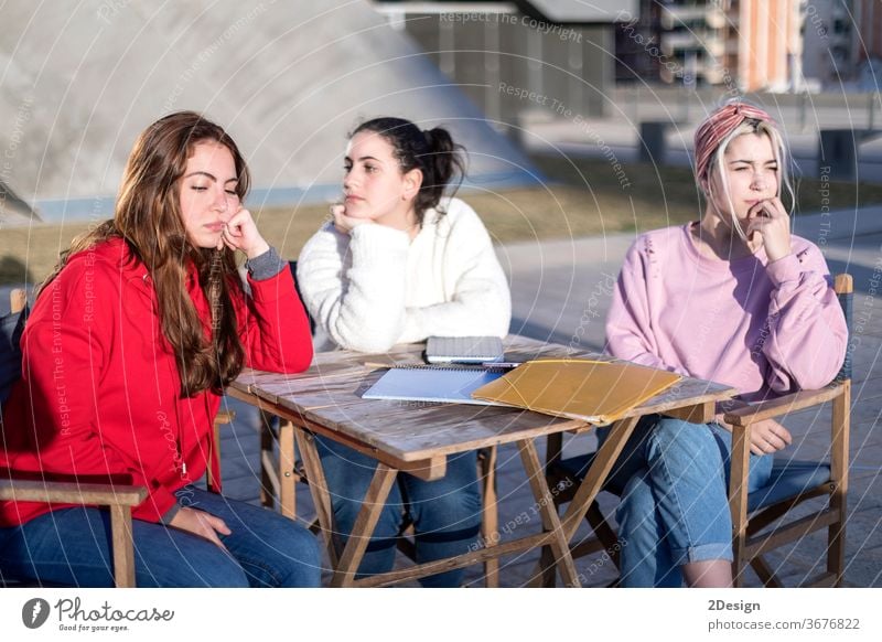 Angry friends or roommates sitting in a cafe outdoors 3 angry upset friendship arguing female girls woman together unhappy disagreement argument fight teenager