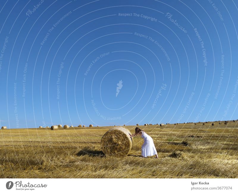 Woman Pushing Hay Bale In Field Hay bale rolling Sky Sunlight scenic Agriculture Farm Harvest Rural Summer