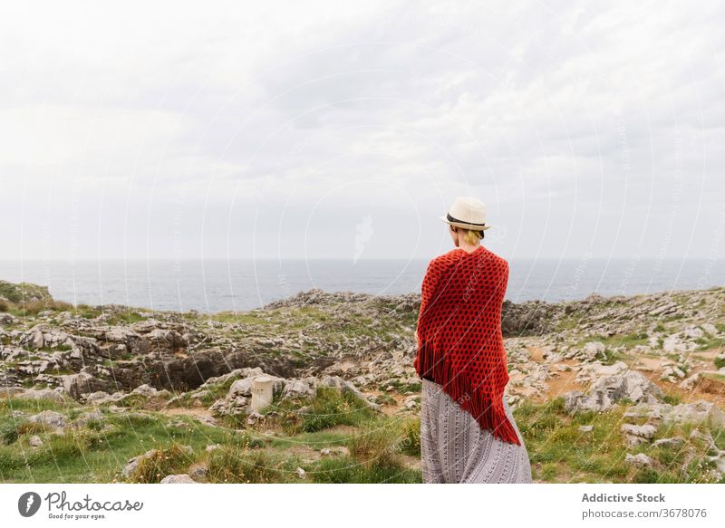 Stylish woman standing near cliff on sea coast travel rocky nature style explore spain asturias adventure wanderlust trendy calm alone wild activity llanes