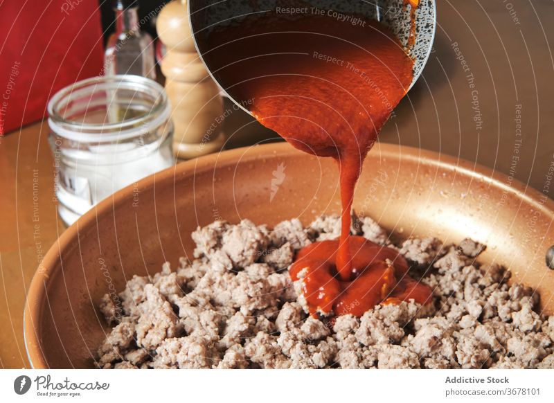 Cook adding sauce into pan with minced meat bolognese tomato ingredient pour prepare cook fried dinner fry hot beef stew aromatic food kitchen cuisine meal