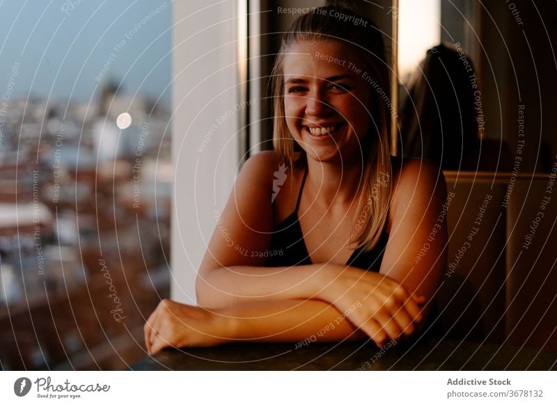 Young happy woman enjoying cityscape from cafe rooftop cheerful window evening smile madrid sunset cozy urban spain glass wall comfort relax restaurant