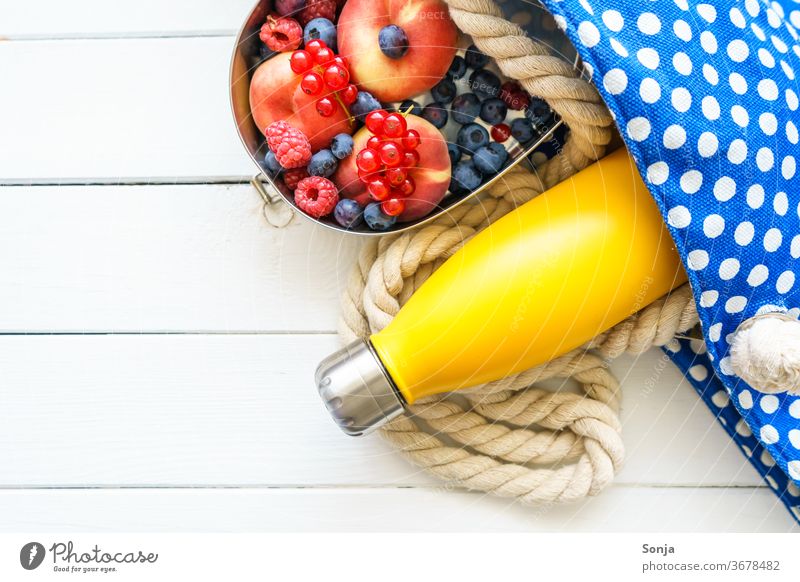 Beach bag with a yellow water bottle and fresh fruit in a tin can. Top view. Bottle of water beach holiday vacation Ocean voyage Summer vacation Colour photo