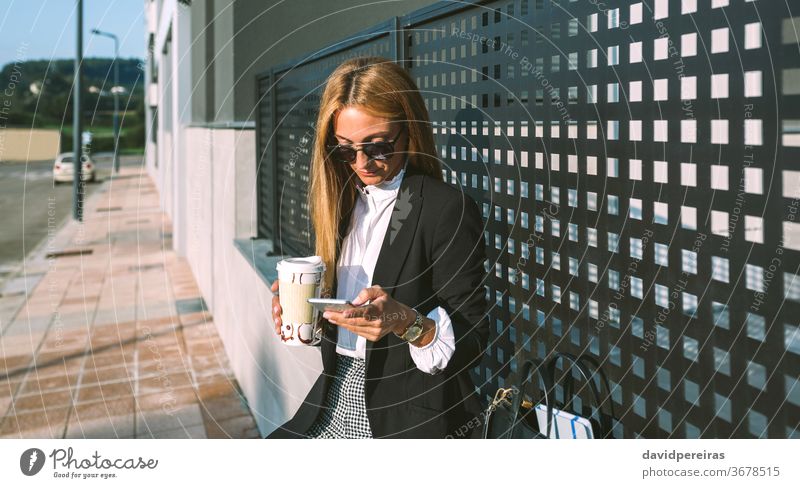 Businesswoman using mobile and drinking coffee take away coffee businesswoman fashion street cell phone texting sunglasses lifestyle people professional urban