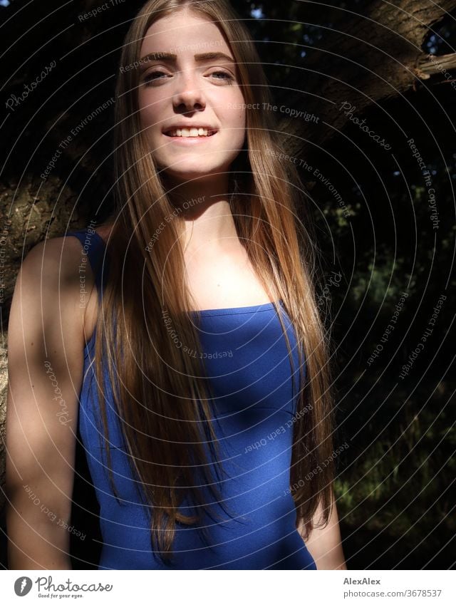 Portrait of a young woman in a blue summer dress in front of a tree with shadow play Purity luck Beautiful weather Trip Expectation Sunlight Close-up Day