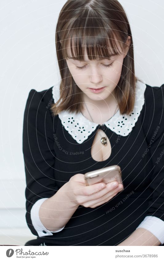 teenager in old fashioned dress looks at her mobile phone Youth (Young adults) Young woman girl Dress Retro distracted youthful portrait Face by hand