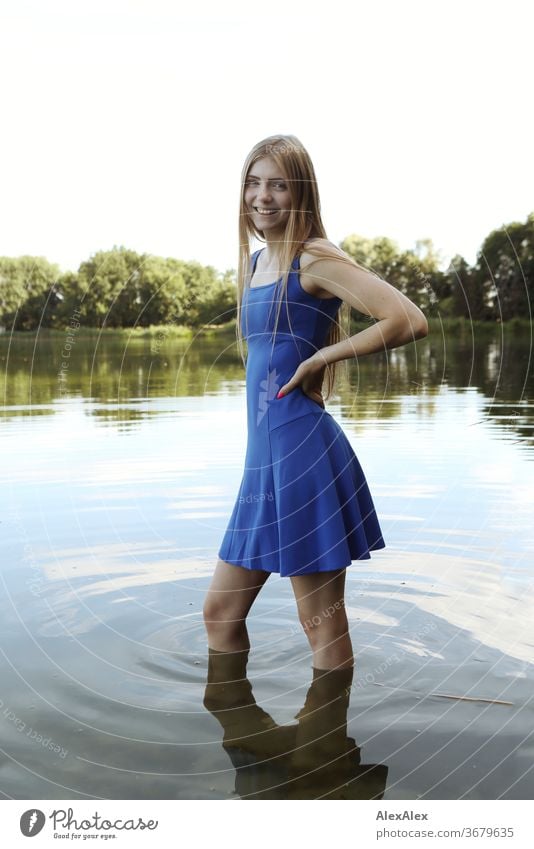 Portrait of a young woman in a blue summer dress in a shallow lake on the shore Purity luck Beautiful weather Trip Expectation Sunlight Close-up Day