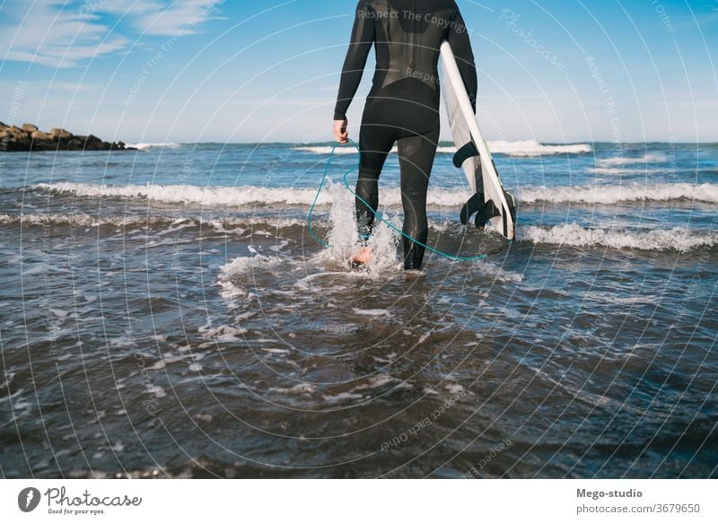Surfer entering into the water with his surfboard. man sport surfing sea surfer ocean outdoors athletic scenic coastline waves background adventure sports