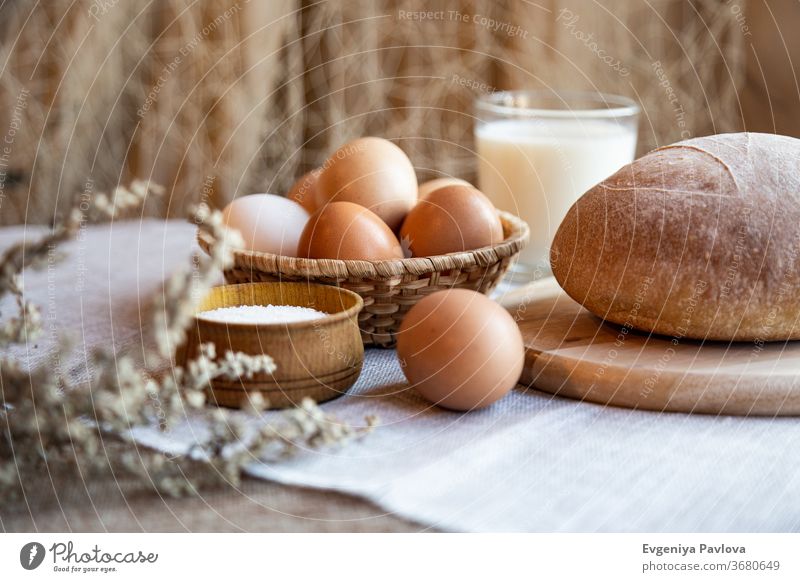 Loaf of fresh homemade bread, milk, eggs and salt on wooden plates. Still life in rustic style bake dough pastry appetizer background bakery beverage breakfast