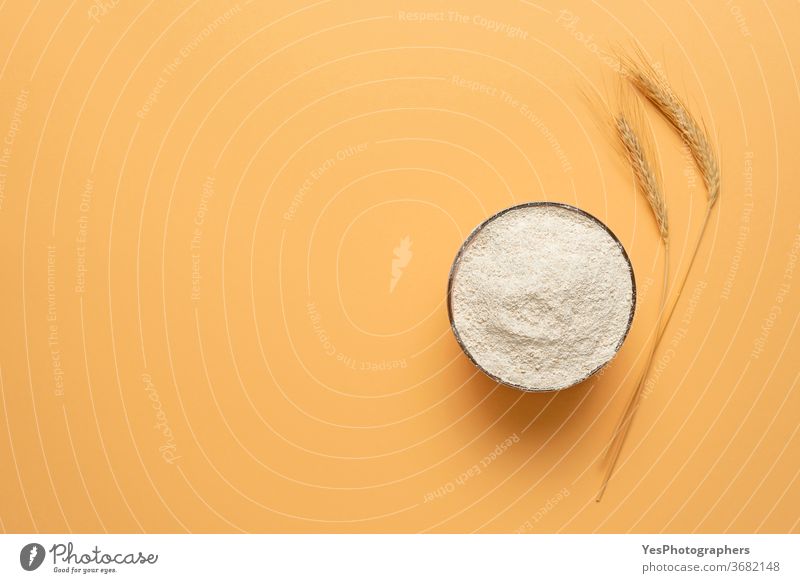 Wholemeal flour in a bowl isolated on a beige background. Bowl of flour top view above view bakery baking banner cereal cooking copy space cream creative layout