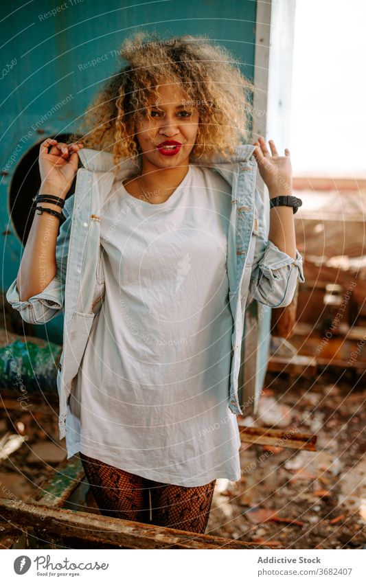 Eccentric ethnic woman in abandoned building millennial style trendy generation grunge independent female black african american city urban stand denim
