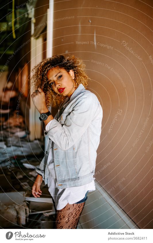 Ethnic woman in abandoned building millennial style trendy generation grunge independent female ethnic black african american city urban stand denim weathered