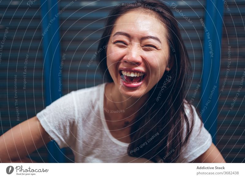 Cheerful young ethnic woman laughing at camera cheerful happy delight having fun excited positive portrait asian glad female casual optimist modern content