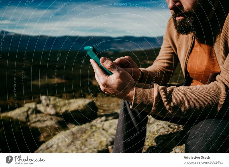 Bearded hiker using smartphone in mountains man countryside sky cloudy rest puerto de la morcuera spain male travel journey mobile relax internet nature trip
