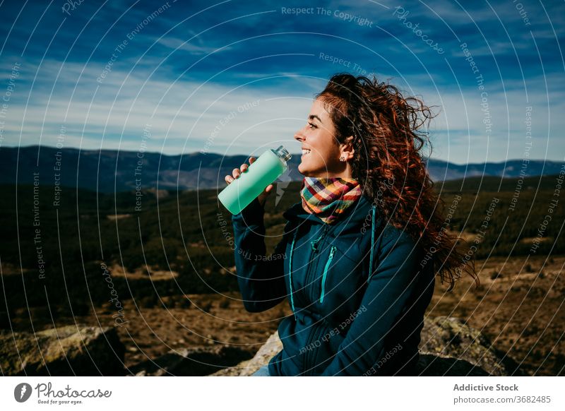 Happy female traveler drinking water in mountains woman smile bottle countryside puerto de la morcuera spain cheerful happy vacation trip journey lifestyle