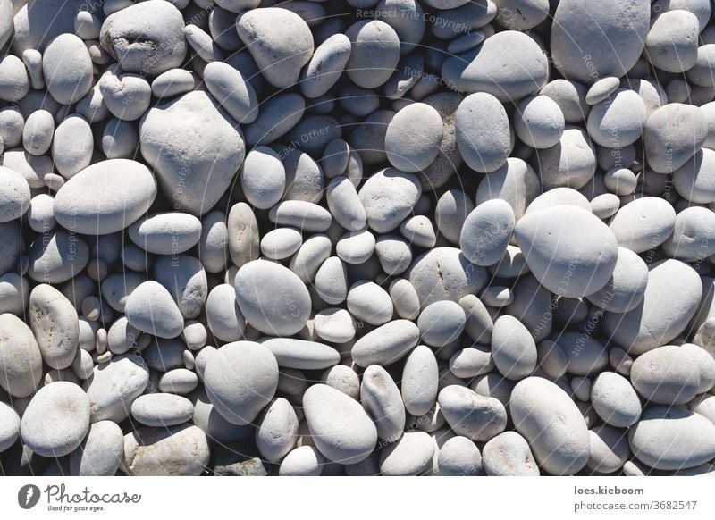 Close up of bright white and grey stones at a beach nature pebble rock background material backdrop pattern natural smooth outdoor texture shape closeup surface
