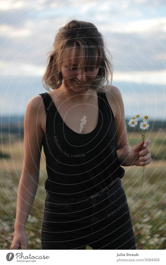 Young woman with camomile flowers in her hand Chamomile Camomile blossom Woman Blonde brunette Black Top Jeans fringe hairstyle Short haircut Flower field