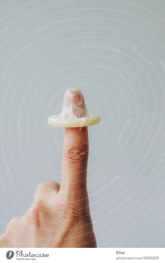A condom on one finger. Topic sexual intercourse and contraception. prevention Condom feminine woman's business go along with by hand Protection Safety