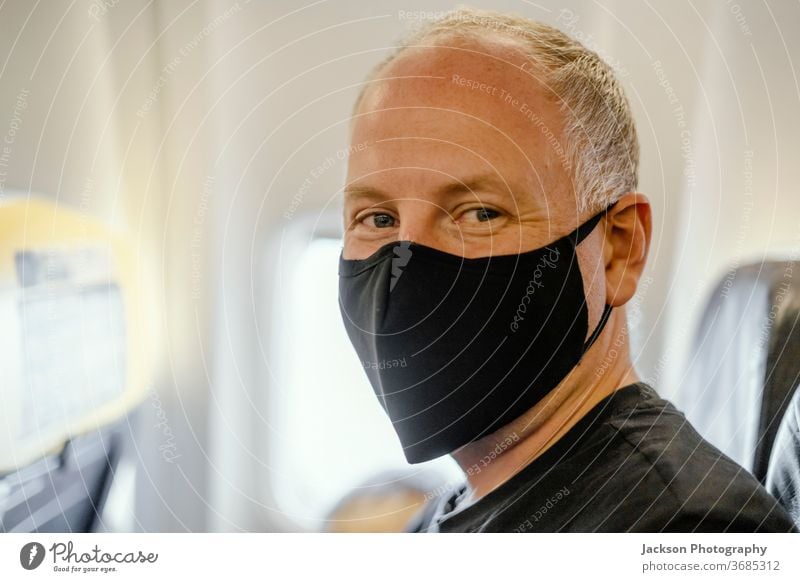 Man sitting in the airplane in protective face mask traveller man prevention disease people virus coronavirus covid-19 happy positive copy space serious