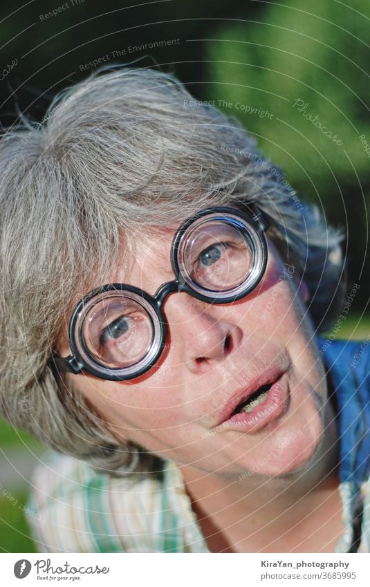 Close-up portrait of a woman with round glasses. Antics and mental health adult eyeglasses fool around gray hair grandmother funny face closeup