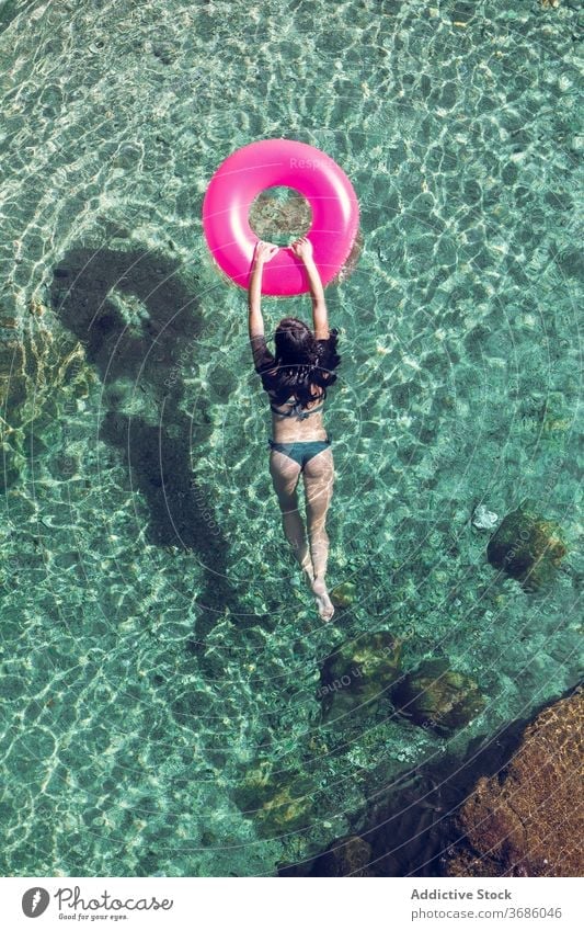 Woman swimming in water with ring woman vacation resort summer swimwear transparent female inflatable tube sunny daytime relax recreation rest holiday tourism