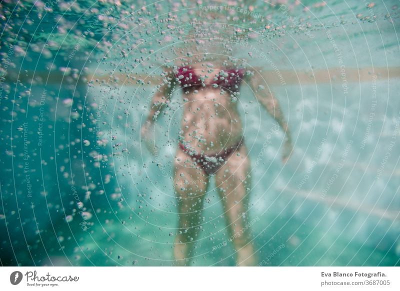 young woman diving floating in a pool. summer and fun lifestyle. selective focus on bubbles. underwater swimming caucasian dive clear health light action wet