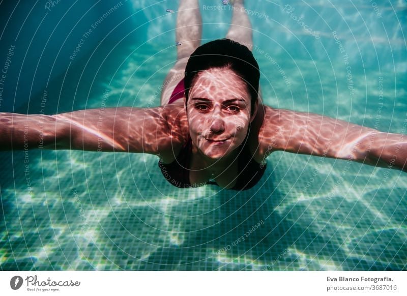 young woman diving underwater in a pool. summer and fun lifestyle swimming bubbles caucasian dive clear health light action wet swimmer blue active float person