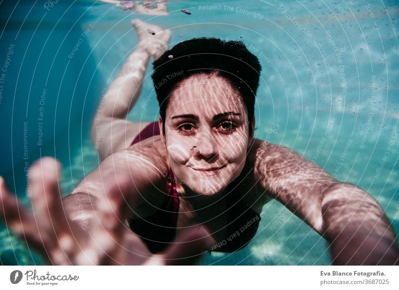 portrait of young woman diving underwater in a pool. summer and fun lifestyle close up swimming bubbles caucasian dive clear health light action wet swimmer