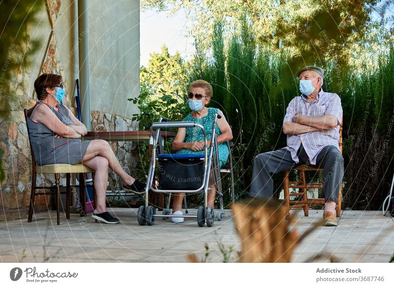 Group of senior people sitting on terrace of house elderly grandparent gather yard together old mask coronavirus protect covid pandemic lifestyle aged