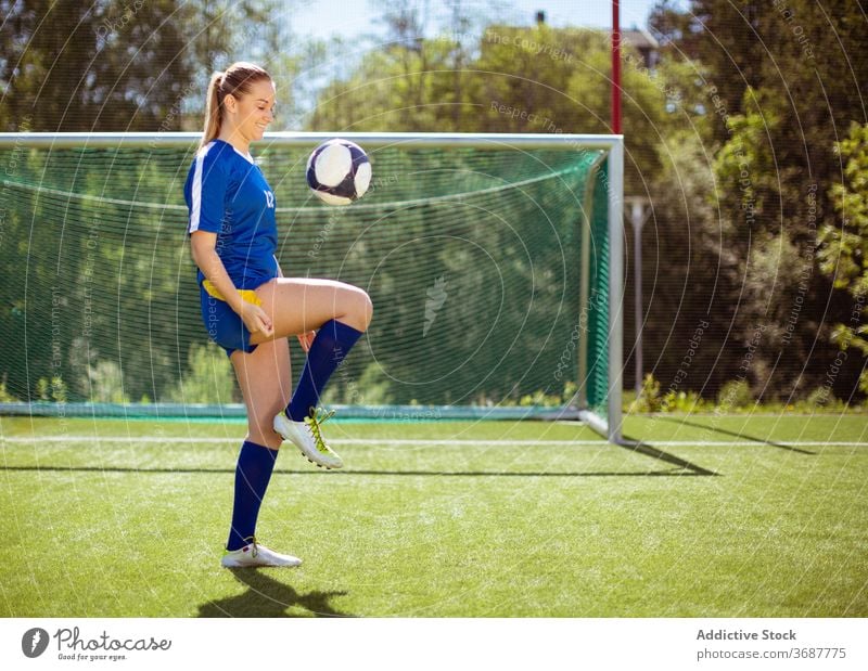 Cheerful football player juggling ball sportswoman juggle field workout smile goal summer uniform female sunny daytime happy training soccer athlete young