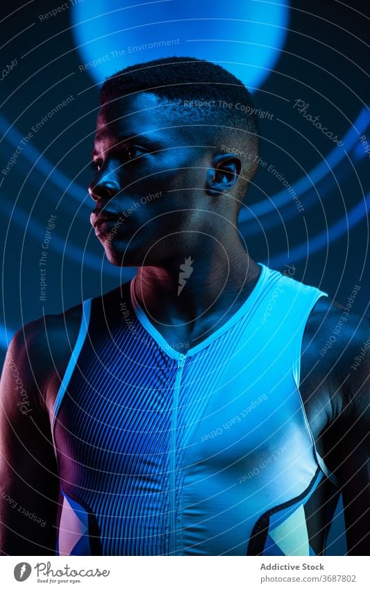 Strong ethnic sportsman looking away athlete confident serious concentrate brutal competitive determine neon challenge blue active physical young black
