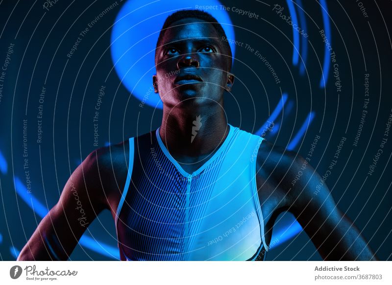 Strong ethnic sportsman looking up athlete confident serious concentrate brutal competitive determine neon challenge blue active physical young black