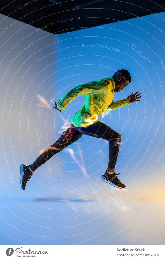 Sportsman starting sprint in studio sportsman runner athlete sportswear determine tracksuit active sprinter jogger physical neon young black african american